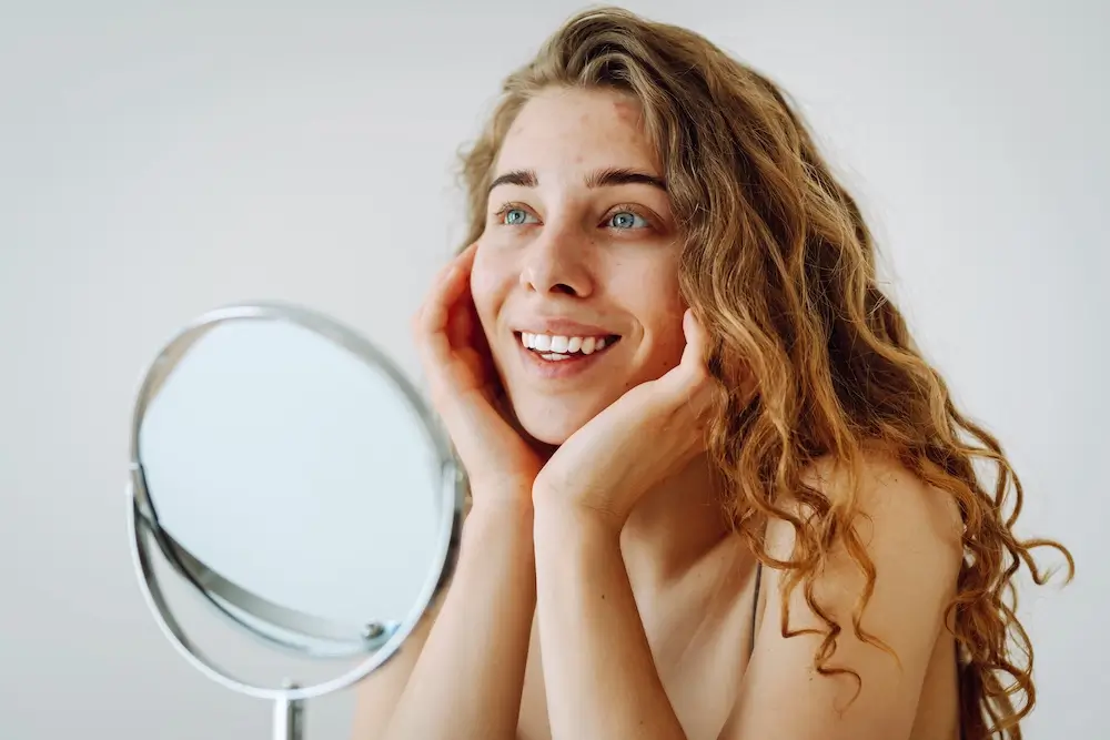 BeautyMark lifestyle image of a smiling client looking into a mirror.